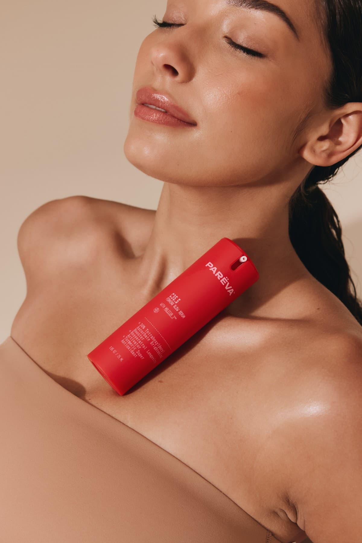 A red Paréva serum bottle resting against a model's collarbone.